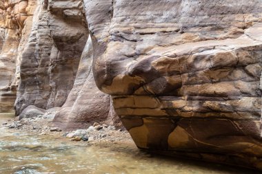 Ürdün, Wadi al Mujib 'deki Mujib Nehri' nin kanyonundaki turizm rotasının sonundaki dağların doğal renklendirilmesi tuhaftır.