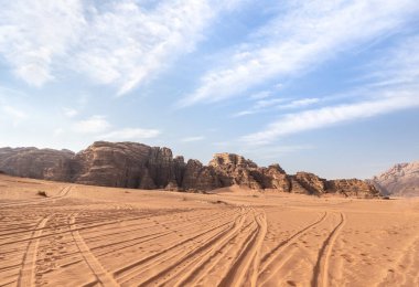 Ürdün 'deki Amman yakınlarındaki Wadi Rum' un sonsuz kumlu çölünde Jeep izleri var.