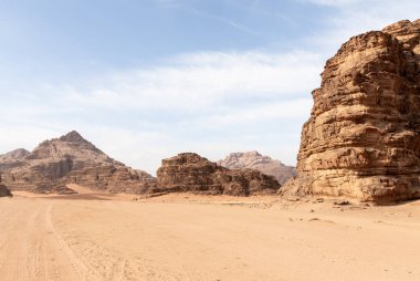 Ürdün 'deki Amman yakınlarındaki Wadi Rum Çölü' nde yüksek dağlarla çevrili kırmızı çölde, off-road aracının lastik izleri var.