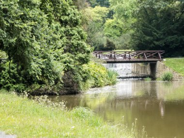 Çek Cumhuriyeti Pruhonice 'daki Pruhonice Şatosu' ndan nehrin üzerinden botanik bahçesine tahta köprü.