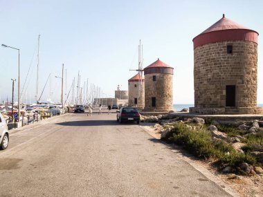 Rodos, Yunanistan, 01 Temmuz 2011: Ünlü Rodos Yel Değirmenleri Yunanistan 'ın Rodos adasındaki Rodos kentinin limanındaki Aziz Nicholas Kalesi' ne doğru yola çıktılar