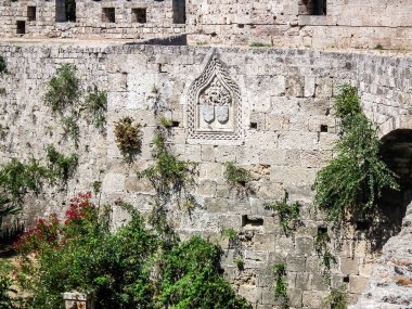 Well preserved bas relief carved from stone on surface of fortress walls in historic part of Rhodes city on Rhodes island in Greece clipart