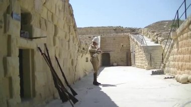 Valetta, Malta, 7 Temmuz 2013: İngiliz mandası asker üniforması giyen aktör, Malta 'daki Fort Rinella' da barut tüfeğinin nasıl kullanılacağını gösteriyor