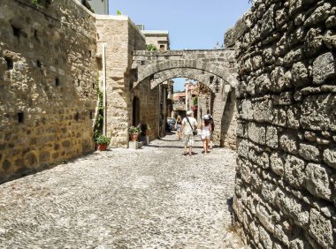 Rodos, Yunanistan, 02 Temmuz 2011: Yunanistan 'ın Rodos adasındaki Rodos kentinin tarihi kesiminde birkaç turist dar sokaklarda yürüyor