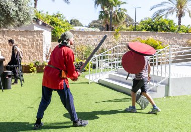 Petah Tikva, İsrail, 18 Nisan 2025: Eğitmen İsrail 'in Petah Tikva kentinde düzenlenen bahar şövalye festivalinde ziyaretçilerle kılıç talimi yapıyor