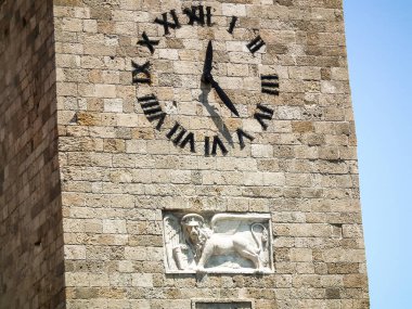 Rodos, Yunanistan, 01 Temmuz 2011: Yunanistan 'ın Rodos adasındaki Rodos şehrinin limanındaki Anonslar Kilisesi' nin çan kulesinde büyük saat ve aslanlar rahatladı