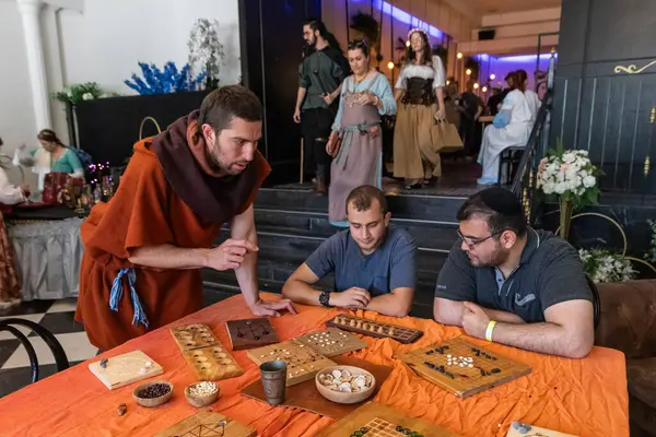 Petah Tikva, İsrail, 18 Nisan 2025: Katılımcı İsrail 'in Petah Tikva kentinde düzenlenen bahar şövalye festivalinde ziyaretçilerle bir ortaçağ masa oyunu oynuyor