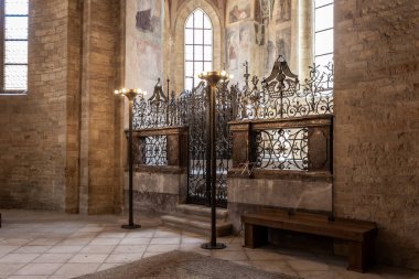 Prag, Çek Cumhuriyeti, 14 Mayıs 2024: Çek Cumhuriyeti Prag Şatosu 'ndaki Aziz Georges Bazilikası' nın ana salonundaki dekoratif demir çitlerin arkasındaki rahip mezarı