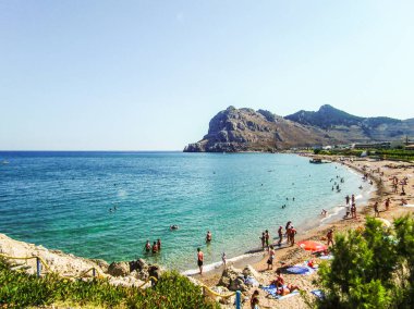 Rodos, Yunanistan, 3 Temmuz 2011: Turistler Yunanistan 'ın Rodos adasının Akdeniz kıyısındaki bir lagünün vahşi plajında dinleniyorlar