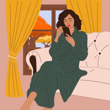 Kız pencerenin yanındaki kanepede sonbahar manzaralı oturuyor. Sonbahar sezonu. Hygge konsepti. Sıcak sonbahar günleri