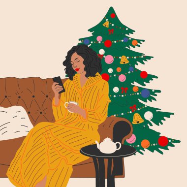 Kız Noel ağacının yanındaki kanepede oturuyor. Hygge konsepti. Sıcak kış günleri