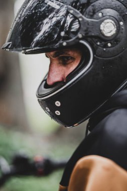 Siyah koruyucu miğferi ve koruyucu giysileri olan bir adam ormanda..