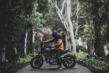 Ormanda motosiklette oturan bir adam.