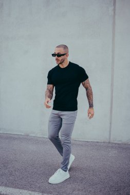 Beyaz tişörtlü, kot pantolonlu, sakallı genç bir adam.