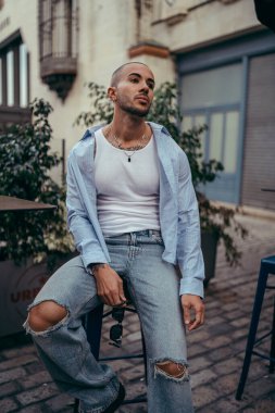 Genç çekici adam merdivenlerde oturuyor.