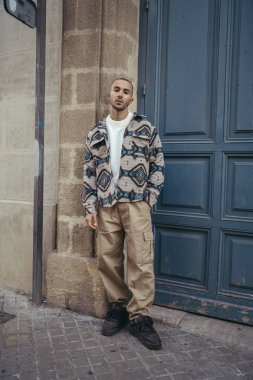 Sokak kıyafetleri içinde poz veren genç bir adam.