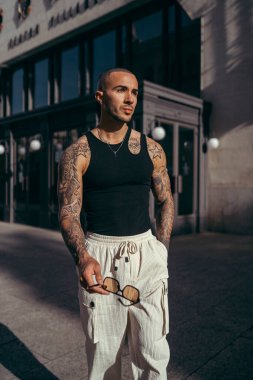 Dövmeli vücuduyla şehir bağlamında poz veren genç adam
