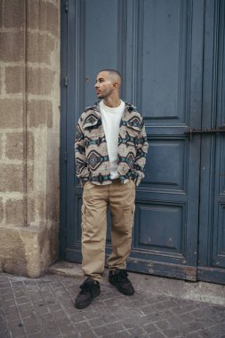 Paris 'te bir sokakta dikilen gündelik elbiseli yakışıklı bir adam.