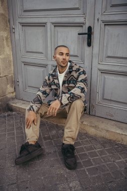 Siyah ceketli, beyaz gömlekli, sokakta çanta taşıyan yakışıklı bir adam.