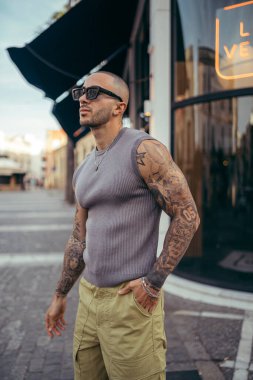 Dövmeli sakallı yakışıklı adam şehirde poz veriyor..