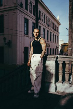 Beyaz tişörtlü ve kot pantolonlu bir gencin portresi.