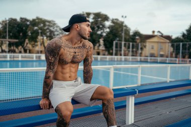 Siyah elbiseli yakışıklı genç adam sokakta poz veriyor.