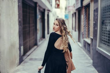 Şehirdeki bir sokakta uzun siyah elbiseli genç ve güzel bir kadın yürüyor. Kız şehirde dolaşıyor..