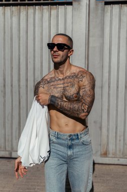 Yakışıklı, genç, güneş gözlüklü, şehirde beyaz vücutlu bir adam.