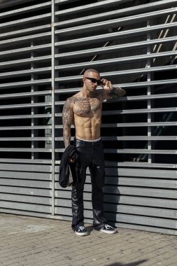 Şehir sokaklarında poz veren dövmeli yakışıklı bir adamın portresi.