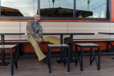 Genç bir erkek bir kafede masada oturuyor.