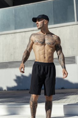 Şehirde poz veren dövmeli yakışıklı kaslı bir adam..