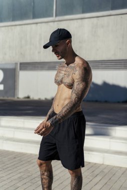 Siyah elbiseli genç adam vücudunun önünde duruyor.