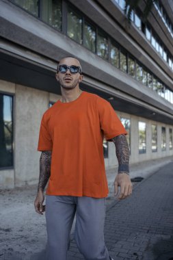 Dövmeli genç adam şehir sokaklarında poz veriyor.