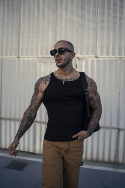 Güneş gözlüklü ve dışarıda poz veren yakışıklı bir adam.