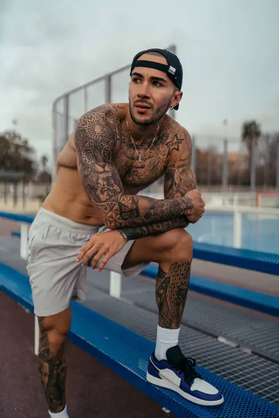 Spor elbiseli genç adam şehrin merdivenlerinde dinleniyor.