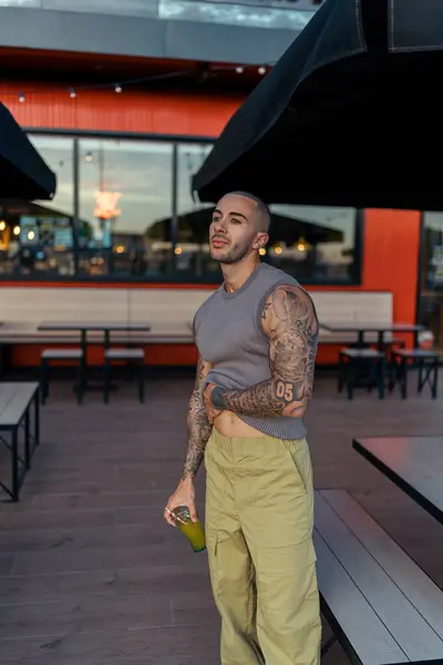 Süslü tişörtlü genç bir adam ve sokakta bir fincan çay.