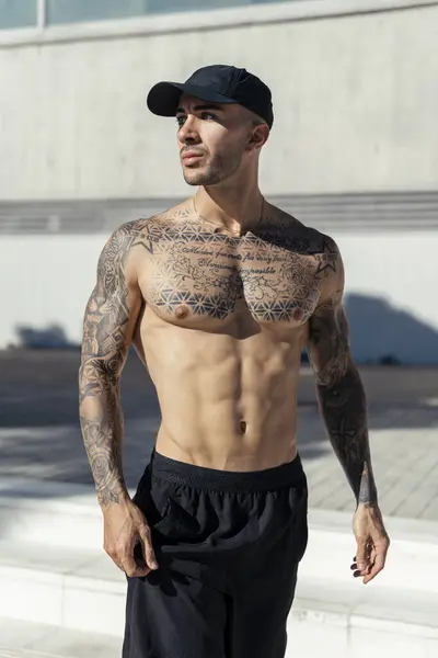 Siyah elbiseli yakışıklı, kaslı bir erkek. Şehir merkezinde poz veriyor..