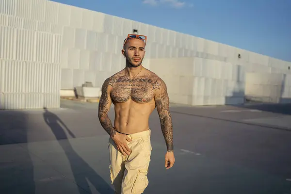 Çatıda poz veren dövmeli genç bir adam.