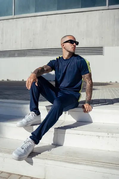 Güneş gözlüğü takan ve şehirde oturan yakışıklı genç adamın portresi.