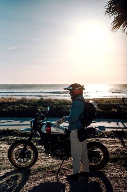 Gün doğumunda plajda motosiklet süren motorcu, sahilde motosiklet süren.