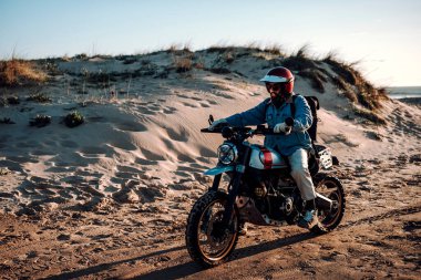 Gün batımında plajda motosikletli bir adam