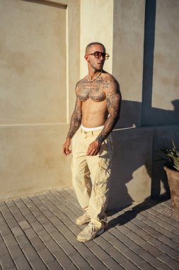 Dövmeli adam kameranın önünde poz veriyor.