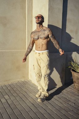 Sokakta poz veren güneş gözlüklü yakışıklı erkek modelin portresi.