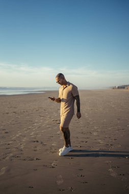 Erkek sporcu gün doğumunda plajda yoga yapıyor.
