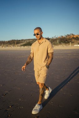 Kumsalda yürüyen bir erkeğin dikey görüntüsü.