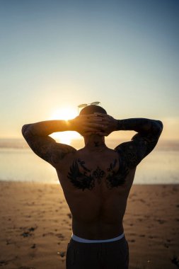 Adam gün doğumunda plajda egzersiz yapıyor..