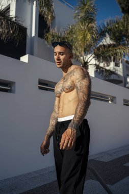 Şehir caddesinde duran dövmeli genç adamın portresi..