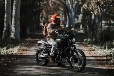 Yolda kask ve motosiklet takan genç bir adam.