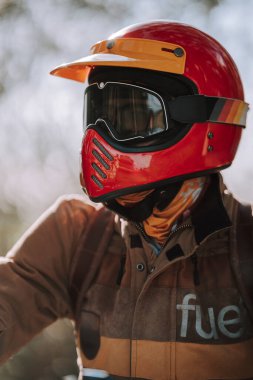 Motosiklet kaskı tutan koruyucu gözlükler takan bir kadının dikey görüntüsü.