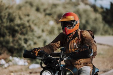 Yolda motosiklet süren kasklı bir adam.